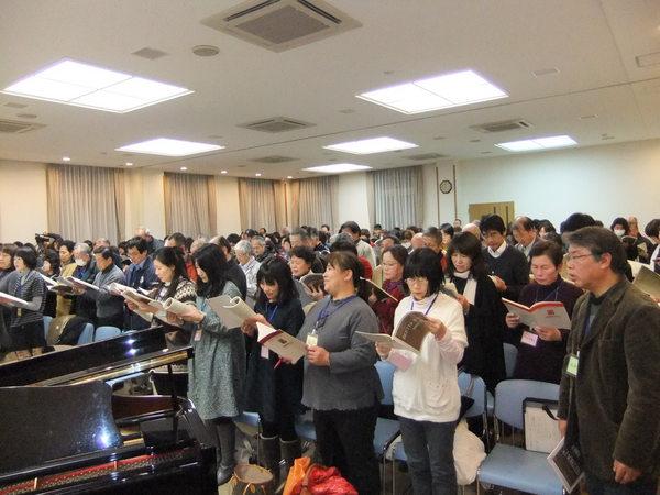 楽譜を両手に持ち、合唱団員が立って歌っている写真